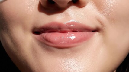 Close Up of a Young Woman Applying Glitter Lip Gloss with a Dewy Shimmer Effect Under Bright Sunlight