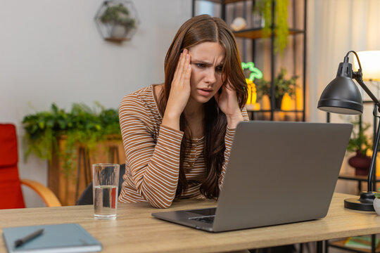 Young woman at home feels eye strain from laptop work rubs temples squints and drinks water for relief. Caucasian girl at desk pauses typing closes eyes breathes slow stretches neck and resumes tasks - Powered by Adobe