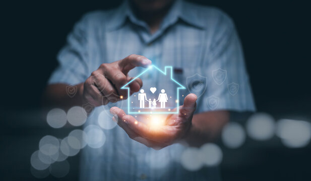 Family protection concept. Businessman holding glowing house icon showing parents and child. symbolizing home security, safety, insurance and future care in modern technology support.