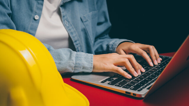 Hands typing laptop beside safety helmet, workplace safety awareness, construction documentation insight, professional responsibility, organized planning and secure workflow concept