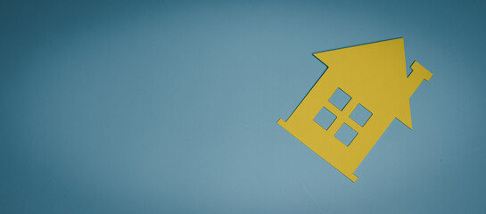 Yellow paper house on blue background, home safety awareness, financial planning, emotional...