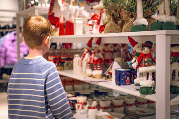 A boy in a store among Christmas decorations. Preparing for the New Year and Christmas. Buying decorations and gifts.