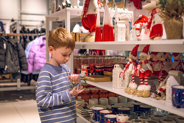 A boy in a store among Christmas decorations. Preparing for the New Year and Christmas. Buying decorations and gifts.