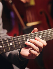 Obraz premium Concert view of acoustic electric guitar player with vocalist and rock band performing in a club, male musician guitarist on stage with audience in a crowded concert club hall arena, hands on guitar