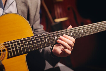 Fototapeta premium Concert view of acoustic electric guitar player with vocalist and rock band performing in a club, male musician guitarist on stage with audience in a crowded concert club hall arena, hands on guitar