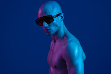 A striking portrait of a confident man wearing stylish sunglasses against a vibrant blue background, showcasing a modern aesthetic and bold colors.