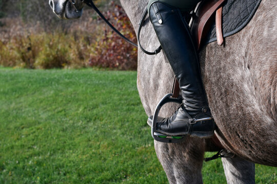 Closeup view of a horse rider&rsquo;s boot resting in the stirrup while mounted on the horse
