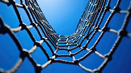 Low angle view of a rope net against a blue sky.