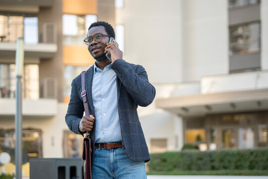 African american businessman talking on phone walking urban street