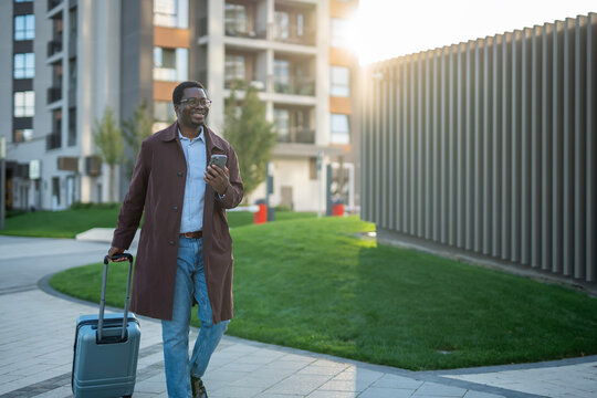 Happy african american businessman walking with luggage