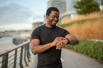Black man smiling using smartwatch tracking fitness progress