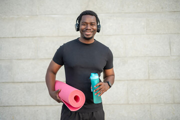 Smiling man ready for fitness workout with yoga mat