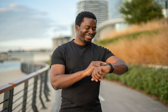Black man smiling using smartwatch tracking fitness progress