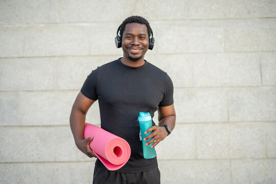 Smiling man ready for fitness workout with yoga mat - Powered by Adobe