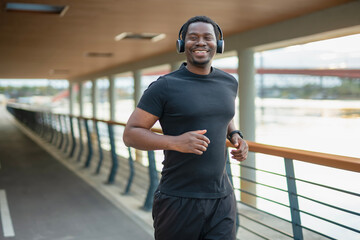 Black man smiling while running on urban bridge