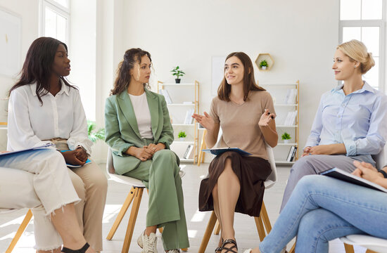 Women group meeting in a training circle. Colleagues share ideas and support each other in a bright office, seated in chairs. Collaboration and wellbeing are encouraged. Team growth concept. - Powered by Adobe
