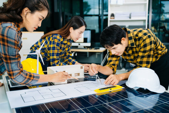 Young professionals collaborate on solar panels and wind turbine models, showcasing teamwork, sustainability, and innovative clean energy solutions.