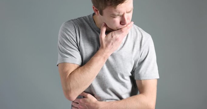 Young man suffering from nausea and stomachache on light grey background. Camera moving down and up