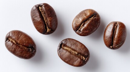 Obraz premium Close-up of five roasted coffee beans, showing rich brown color and textures on white background