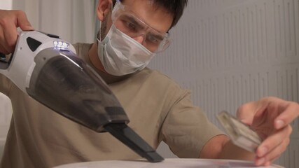 Person safely removing dust from robot vacuum with handheld device, Maintenance scene showing user cleaning robot vacuum filter while wearing safety equipment and gloves