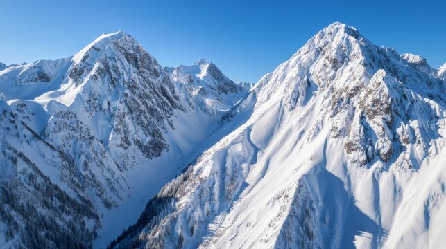 Aerial view of snow-covered Alps with a clear blue sky, showcasing breathtaking natural beauty and majestic mountain peaks.