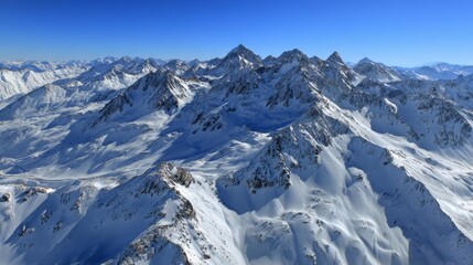 Obraz premium Aerial view of snow-covered Alps with a clear blue sky, showcasing breathtaking natural beauty and majestic mountain peaks.