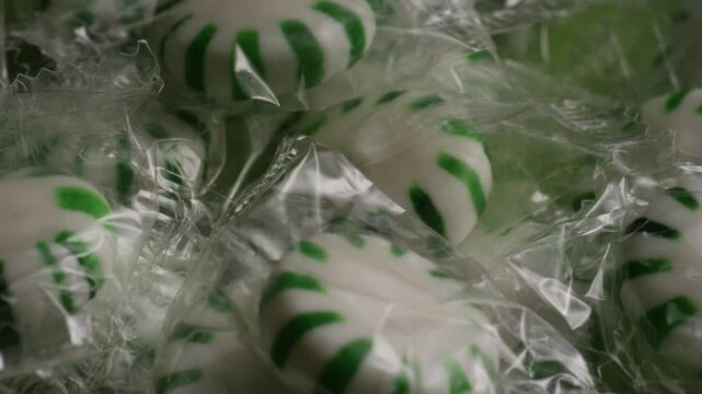 Macro rotating close up view of wrapped green and white striped peppermint hard candies representing St Patricks Day treats and Christmas holiday sweet dessert concepts