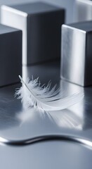 A close-up of a delicate white feather resting on a reflective metallic surface with blurred geometric objects in the background