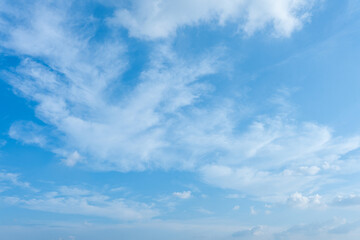 Bright blue sky filled with wispy white clouds in a natural atmospheric background texture
