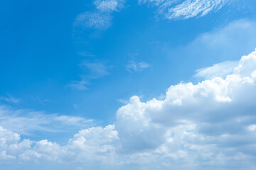 Vibrant blue sky with bright white cumulus clouds dominating the lower right area