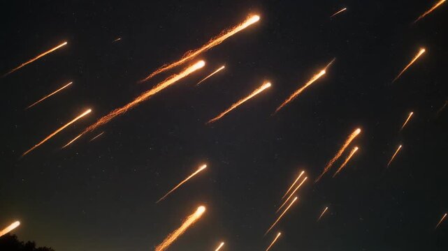 Streaks of light illuminate the night sky over a dark landscape