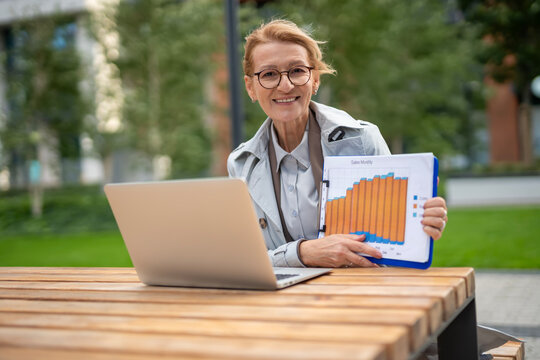 Senior businesswoman presenting sales monthly growth report outdoors
