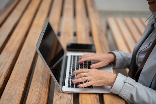 Woman hands typing on laptop working remote outdoors
