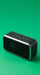 A compact portable Bluetooth speaker with control buttons on top, set against a vibrant green background, showcasing modern audio technology design