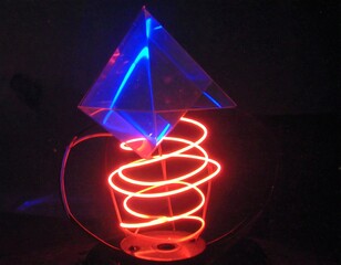 A geometric transparent shape with glowing internal light atop a red spiral against a black background