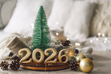 Decorative candles and a small Christmas tree create a cozy scene celebrating the New Year in winter 2026