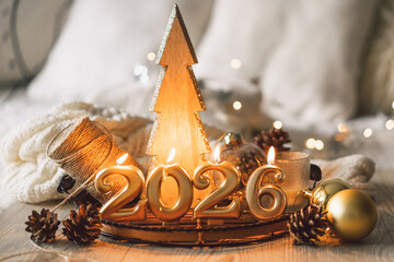 Decorative candles and a small Christmas tree create a cozy scene celebrating the New Year in winter 2026