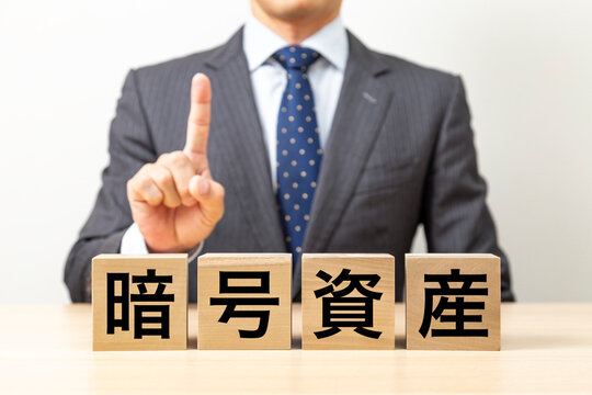 「暗号資産」と書かれたブロックとビジネスマン - Powered by Adobe