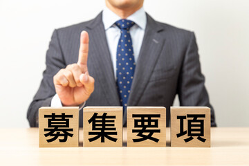 「募集要項」と書かれたブロックとビジネスマン