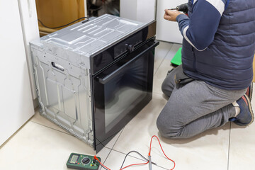 Technician installing electric oven in a modern kitchen