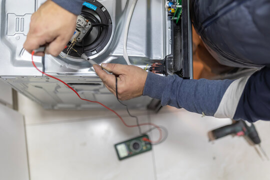 Technician troubleshooting home appliance electronics with multimeter