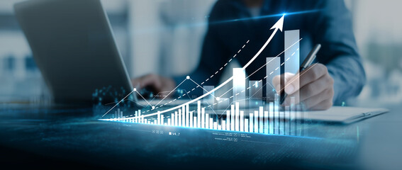 Businessman working with laptop and growing graph with upward trend arrow.  Growing forex chart on blurry background. Financial investment and economy concept. © Benjamin