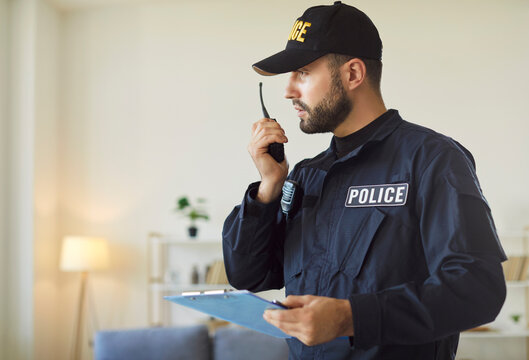 Policeman or detective communicates via wireless radio and completes a report at a crime scene, showcasing the dedication of law enforcement during criminal investigations and legal processes.