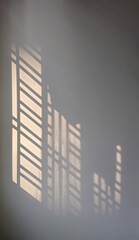 Abstract window sunlight on an empty white wall creates a textured background.
