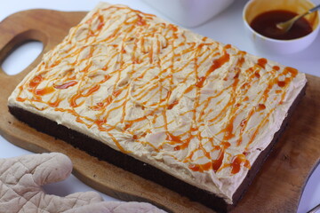 Chocolate sheet cake with a thick layer of buttercream frosting, drizzled with caramel cream sauce