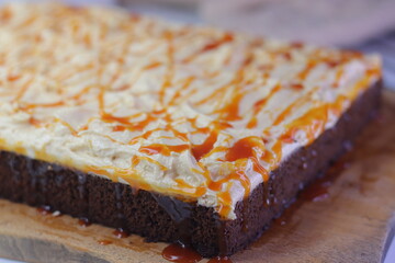 Chocolate sheet cake with a thick layer of buttercream frosting, drizzled with caramel cream sauce