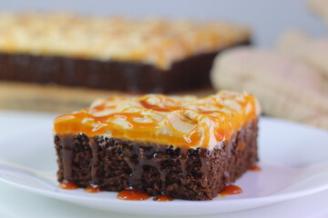 Moist chocolate cake slice topped with buttercream frosting and drizzled with caramel cream sauce.