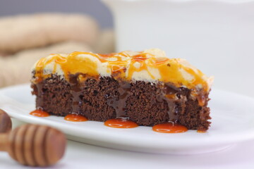 Moist chocolate cake slice topped with buttercream frosting and drizzled with caramel cream sauce.