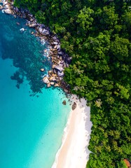Aerial view of a stunning tropical coastline featuring vibrant turquoise water, white sand, and lush green vegetation