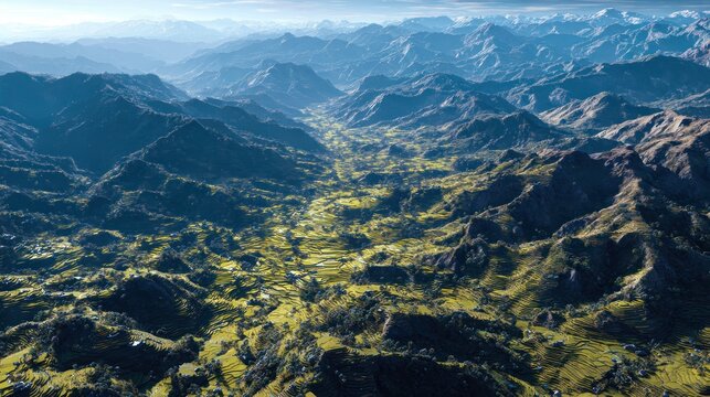 Aerial View of Mountainous Terrain with Green Valleys and Terraced Fields in Bright Sunlight